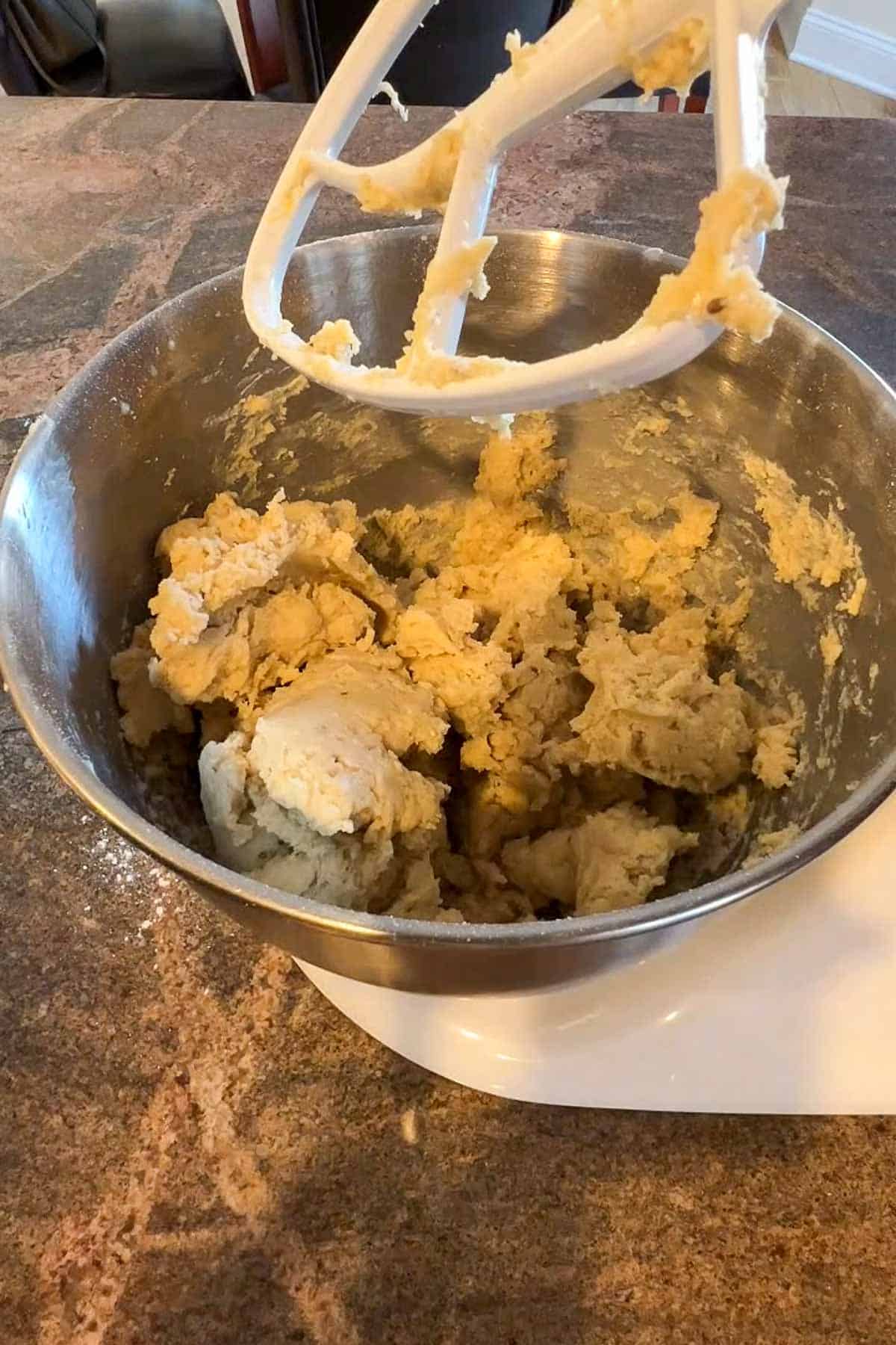 Cookie dough in the metal bowl of a stand mixer.