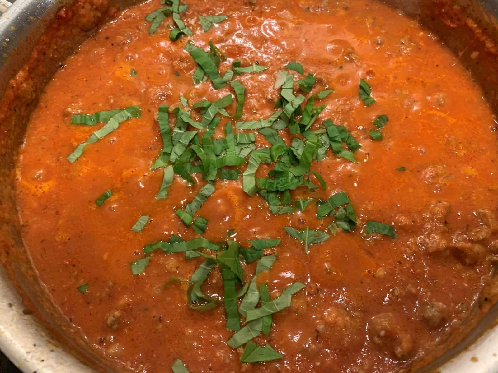 A pan of vodka sauce with fresh basil on top.