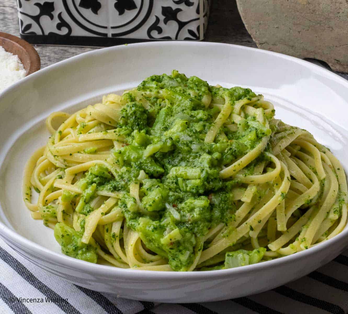 A white bowl of linguine with a broccoli sauce.