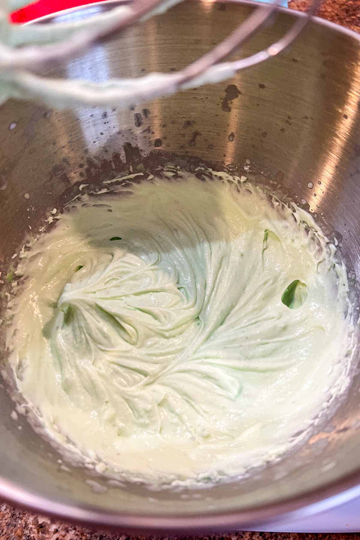 Pistachio whipped cream frosting in a metal bowl.