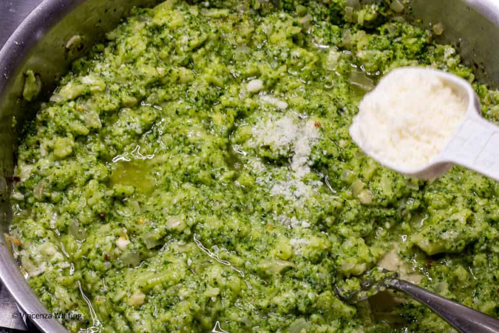 Grated romano cheese is added to mashed broccoli.