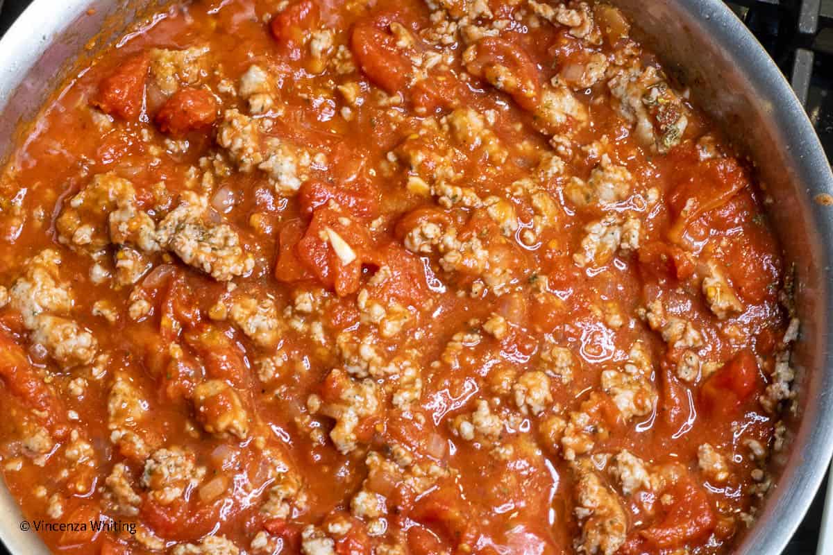 Tomato sauce with groudn sausage in a skillet.