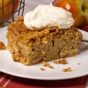 A piece of apple cake with whipped cream on top.