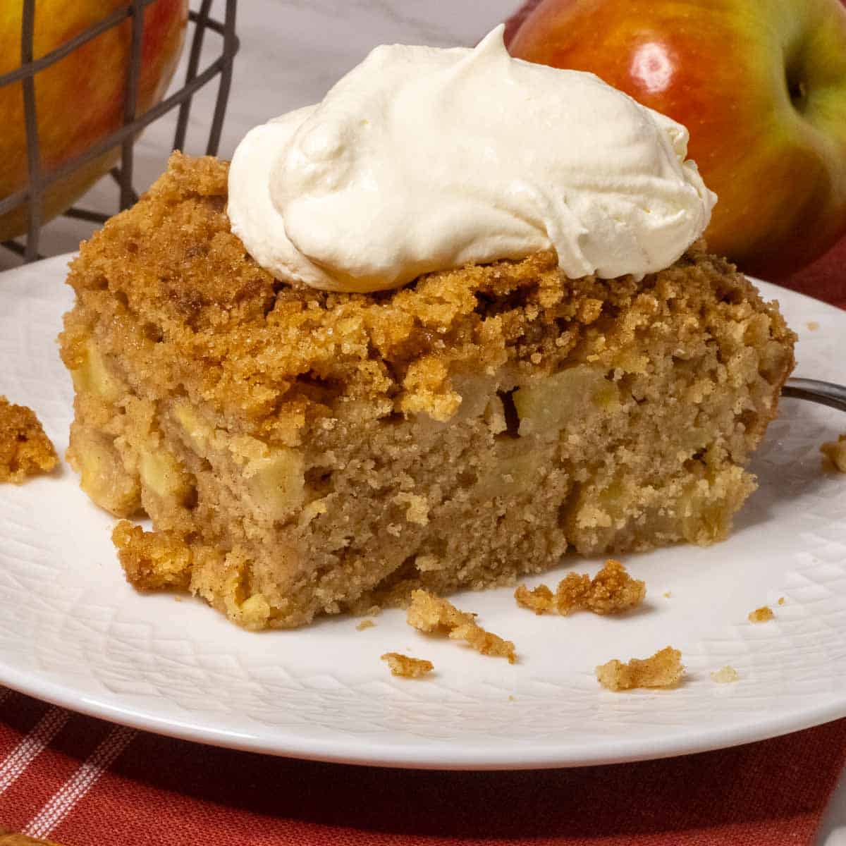 A piece of apple cake with whipped cream on top.