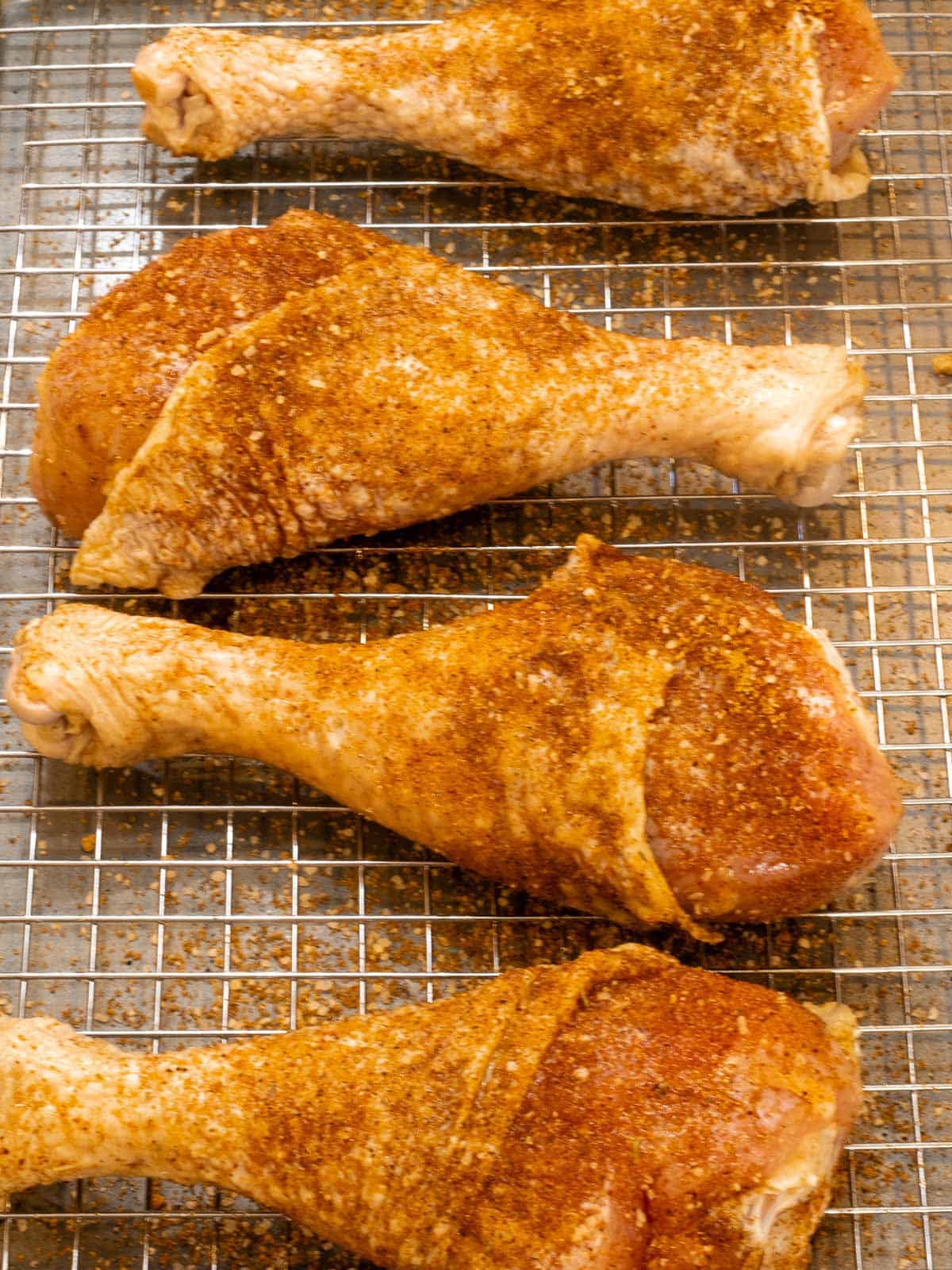 Raw turkey legs covered in seasoned dry rub on a grate.