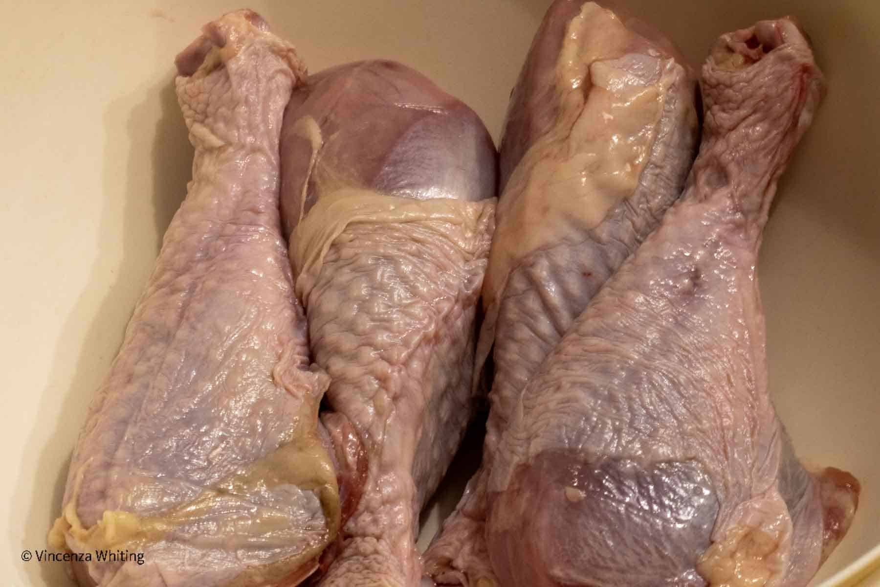 Raw turkey legs on a white cutting board.