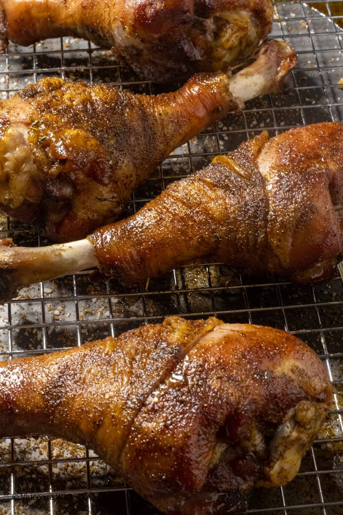 4 smoked turkey legs on a metal rack.