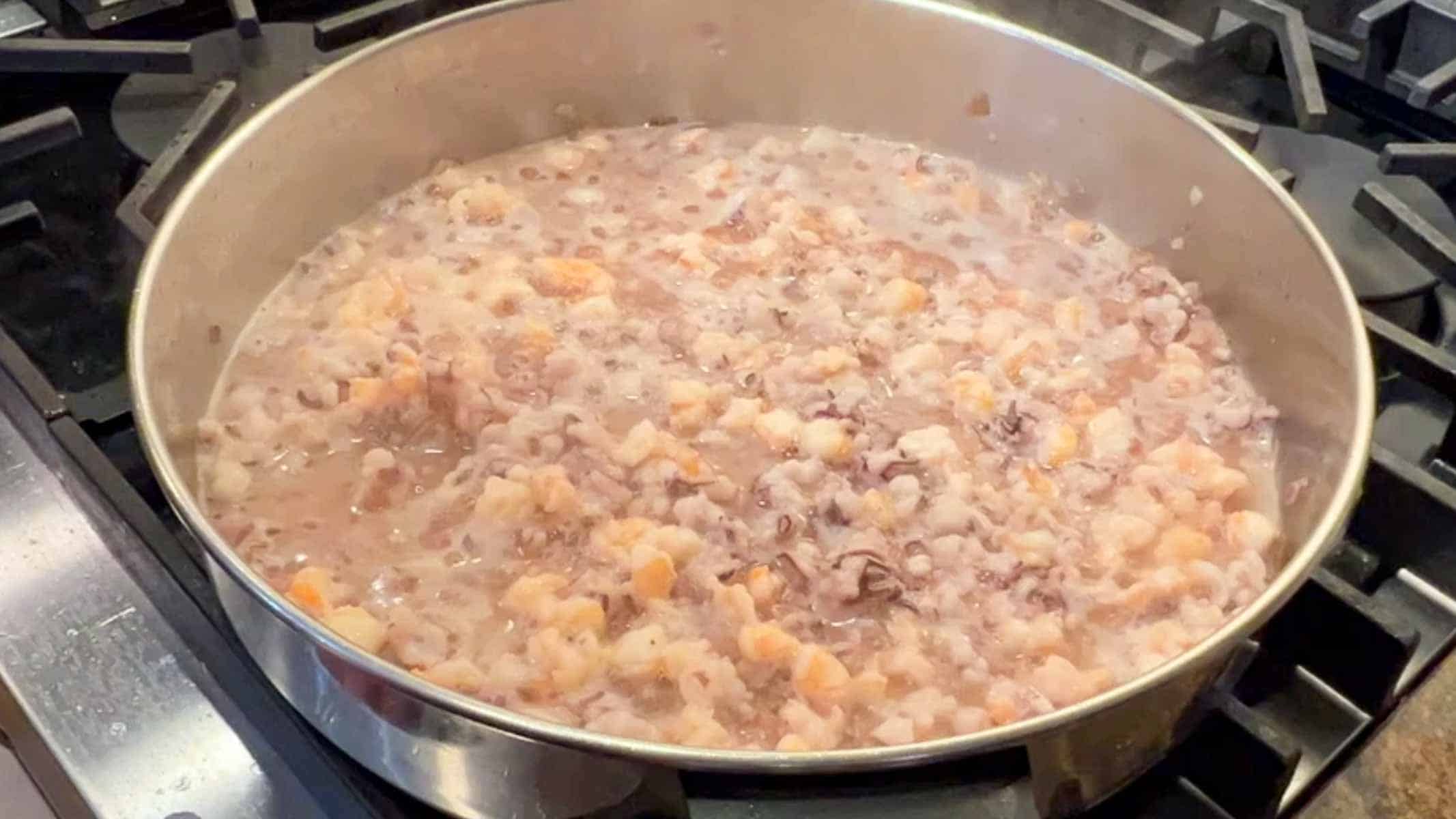 Chopped calamari and shrimp cooking in a saute pan.