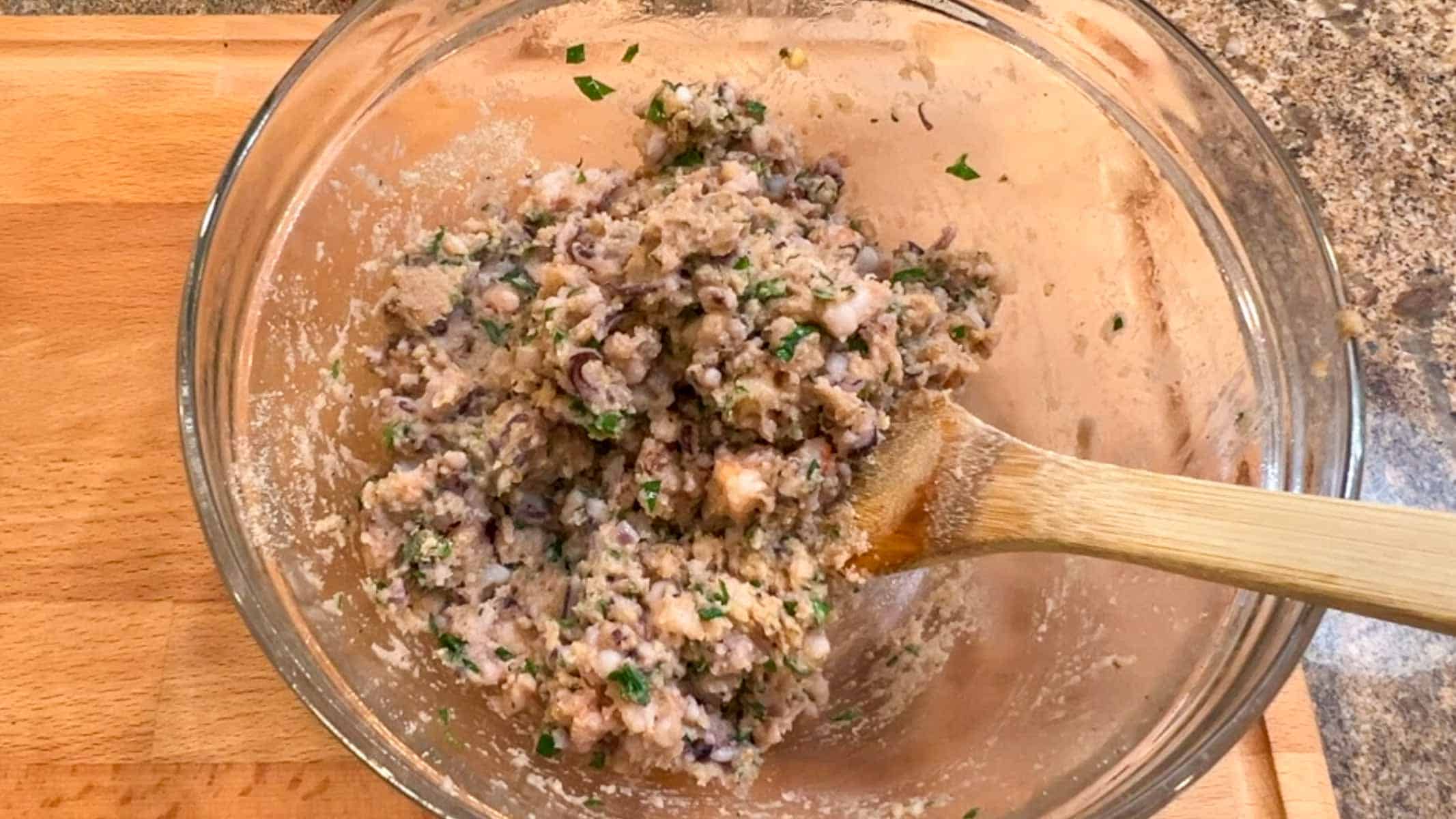 Mixing calamari filling with a wooden spoon.
