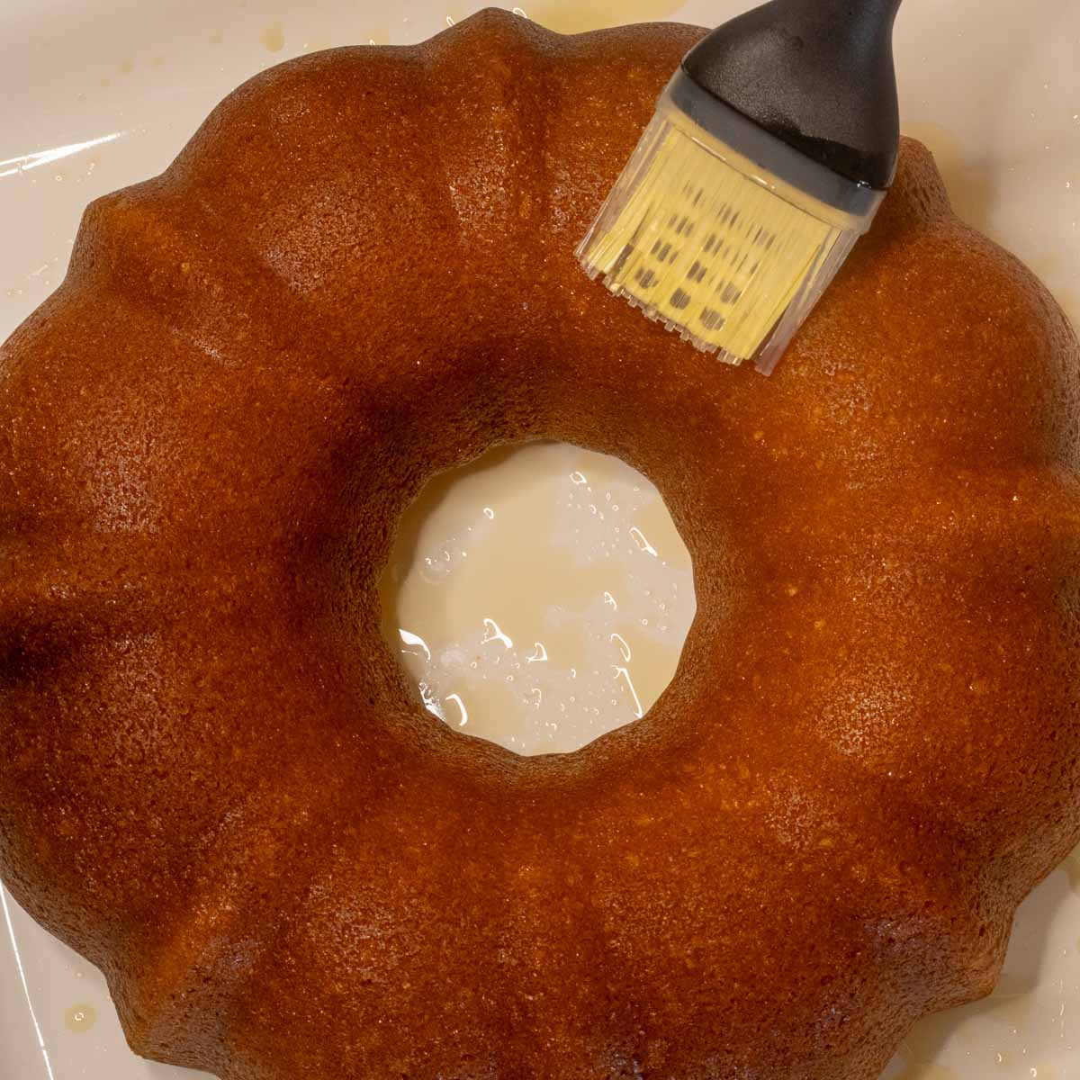 An Italian Hangover cake Bundt cake being brushed with liquour.