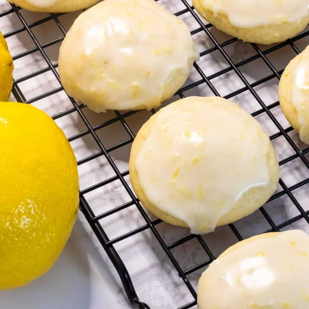 Lemon ricotta cookies on a drying rack next to a lemon.