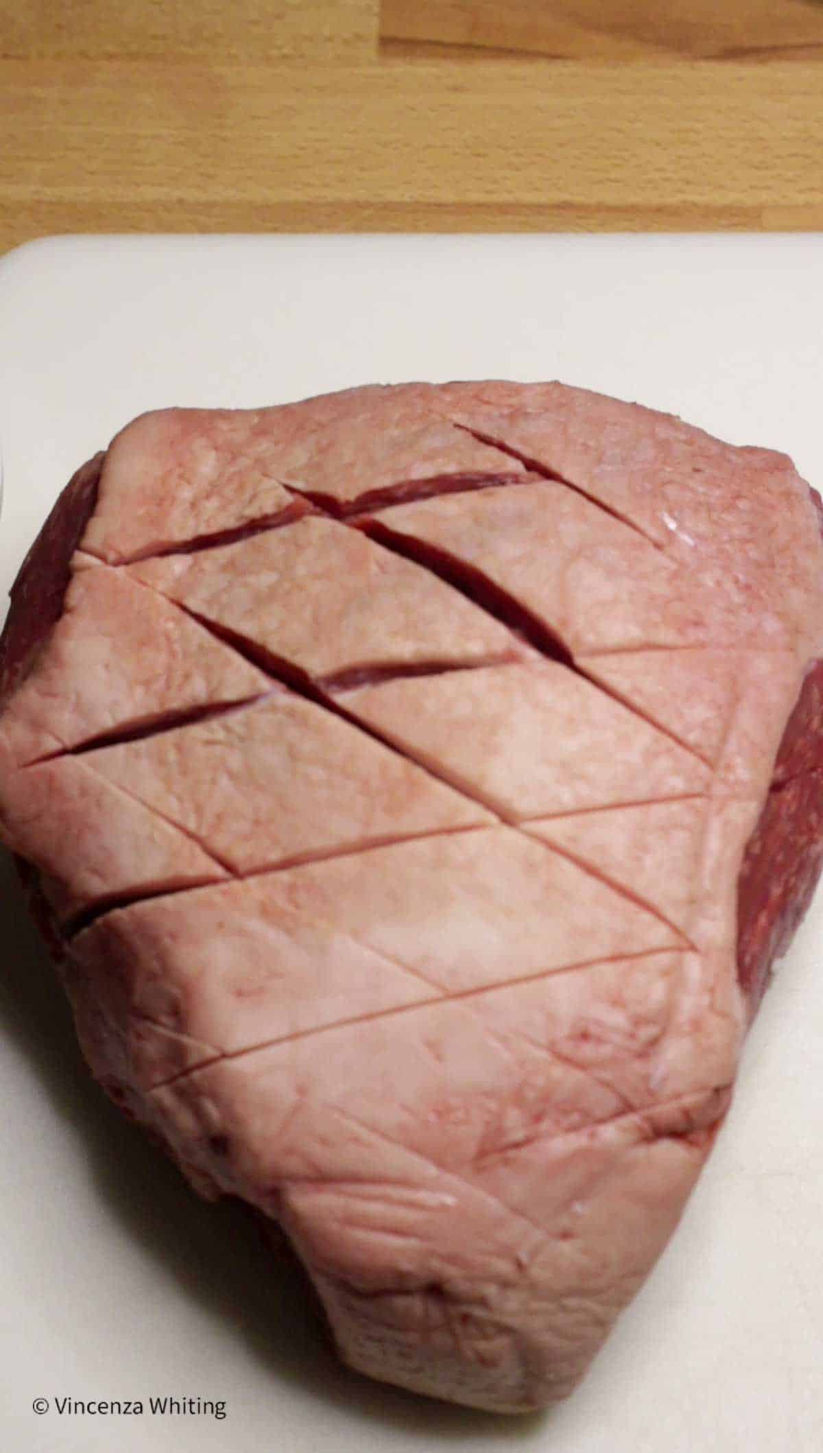 A bottom round roast with diamond shaped slits in the fat cap.