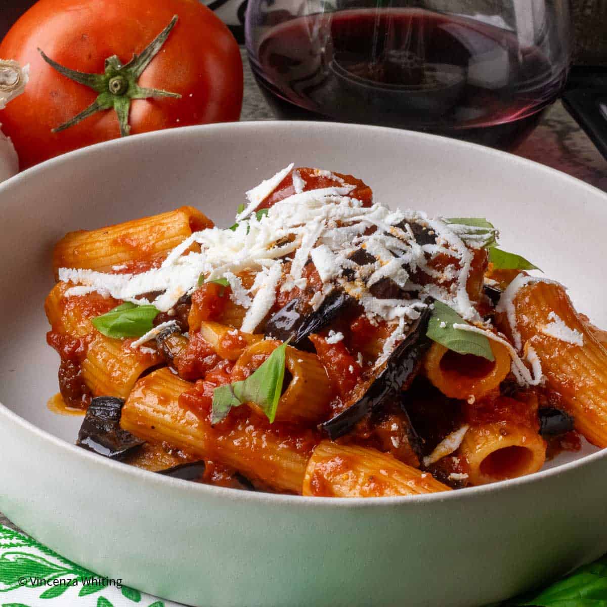 A bowl of pasta alla norma, pasta with a tomato and eggplant sauce topped with grated cheese.