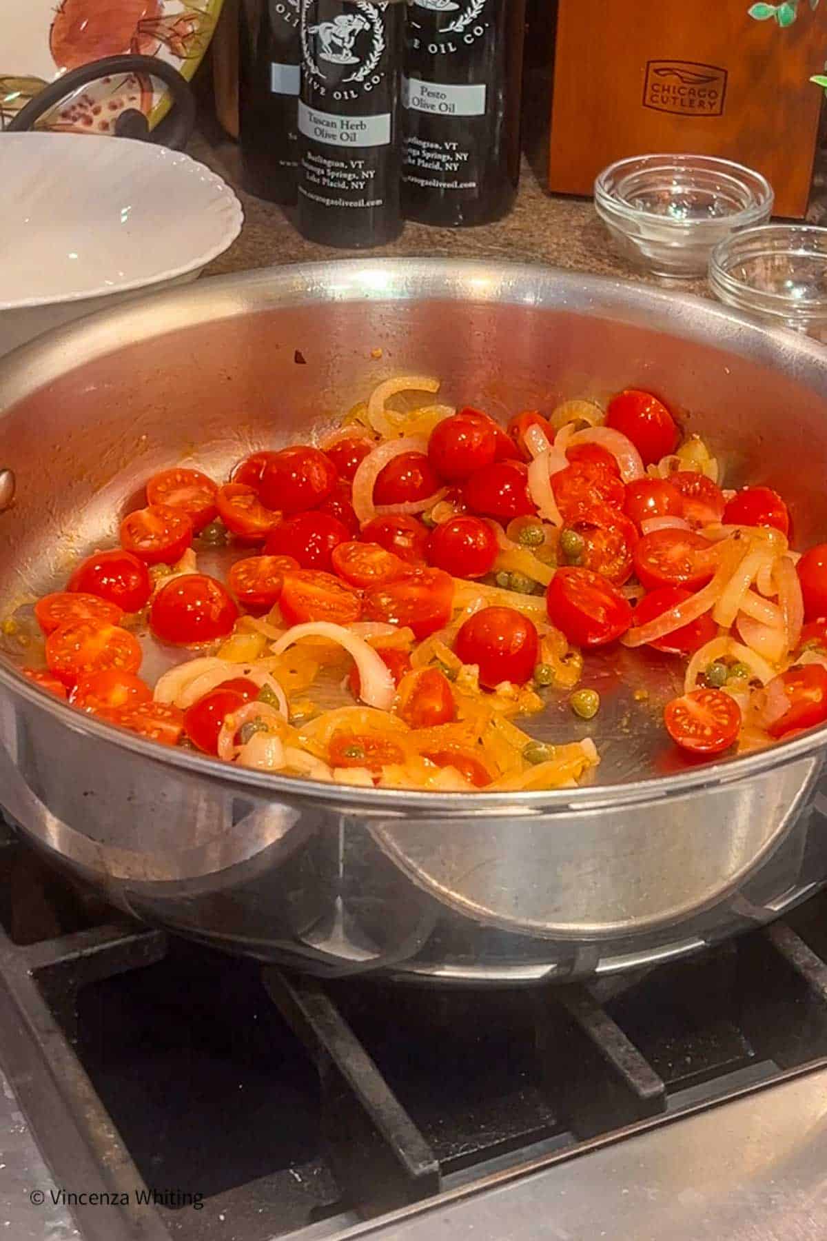 A large sauté pan with cherry tomatoes and onion.  
