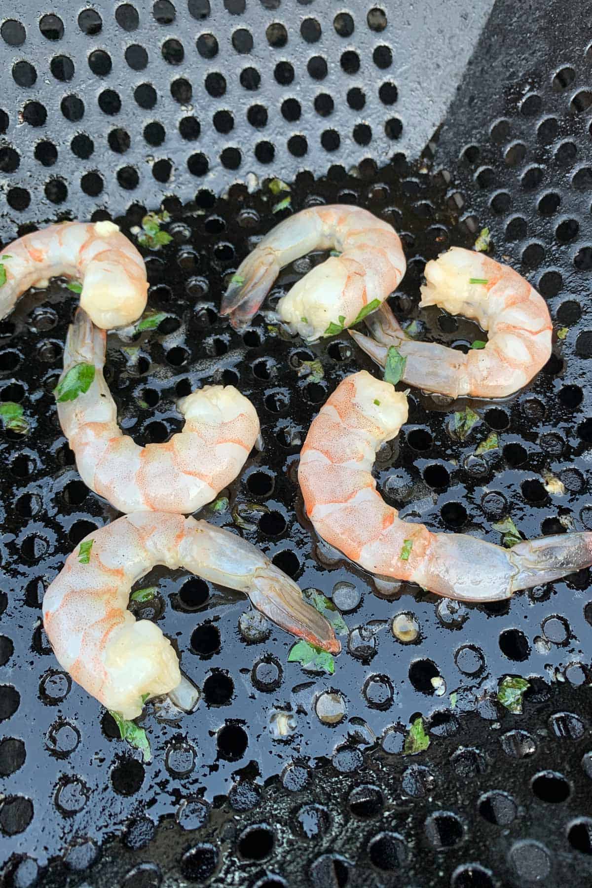 Raw shrimp in a grill basket.