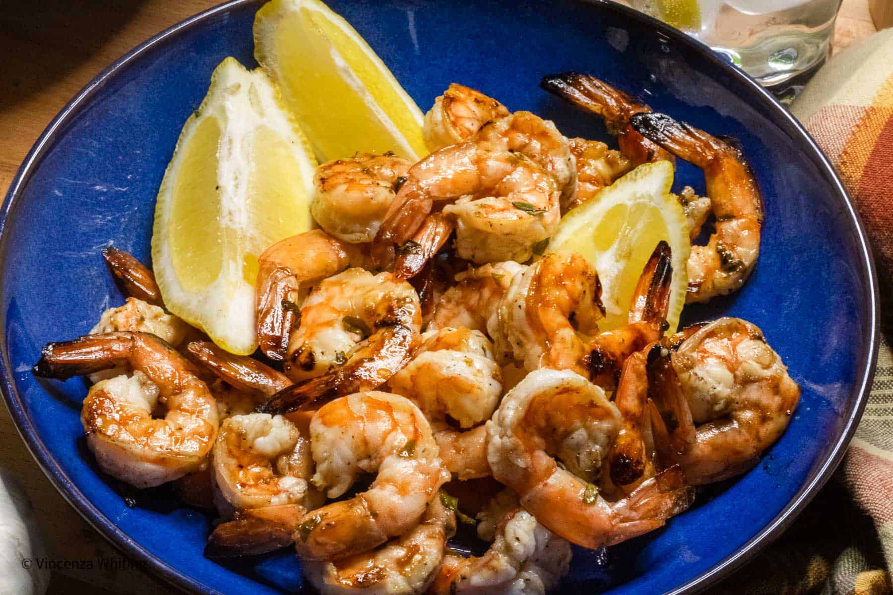 grilled shrimp on a blue plate with lemons.