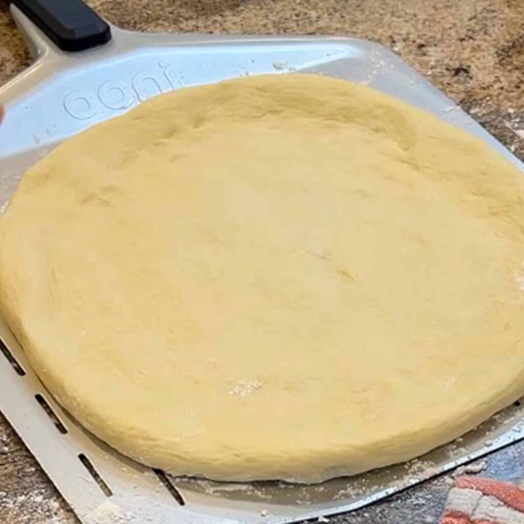 A round of pizza dough on a peel ready fof the oven.