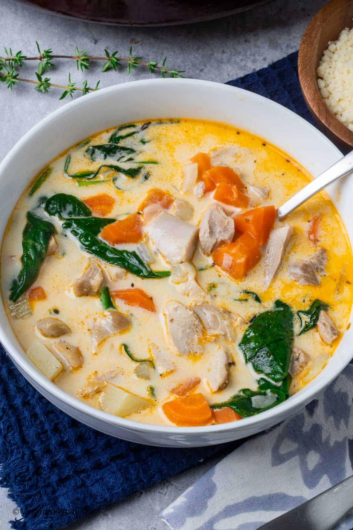 A bowl of creamy chicken soup on a blue cloth.
