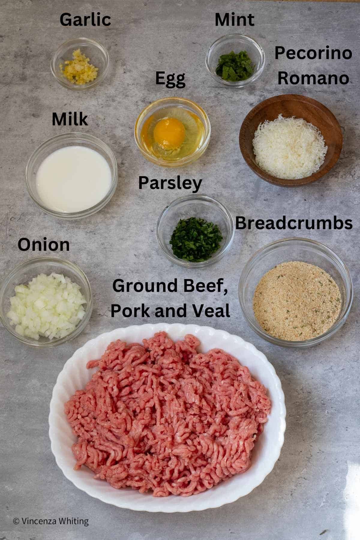 Ingredients needed for making polpette (Italian meatballs) on a gray background.
