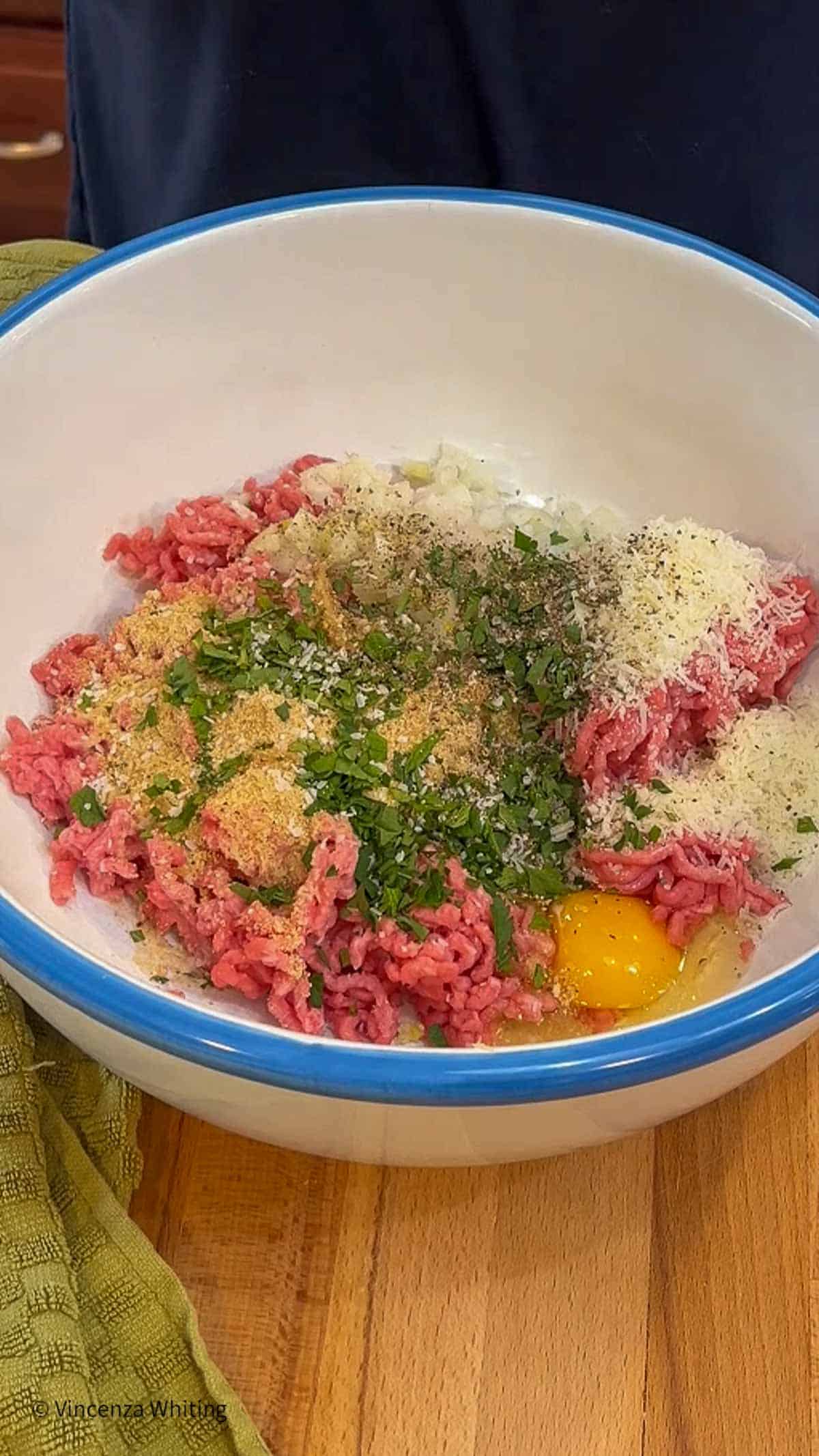 All of the ingredients for making meatballs in a white bowl.
