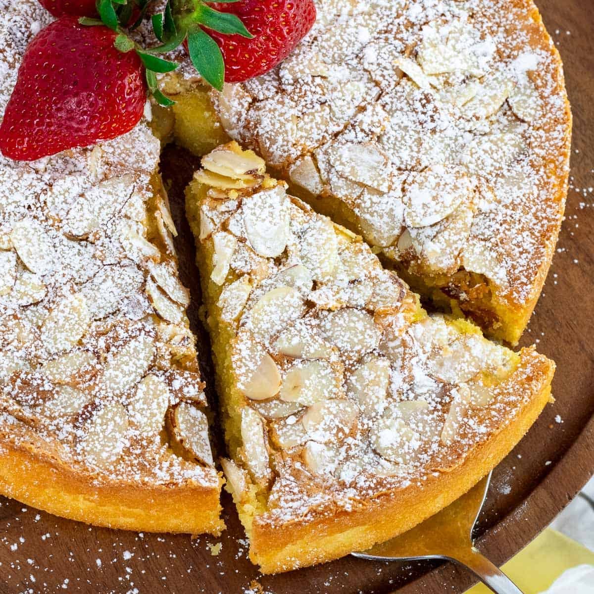 A slice of Italian almond cake is being lifted away from the cake.