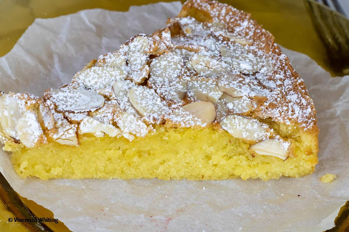 A slcie of almond cake on a piece of parchment paper.