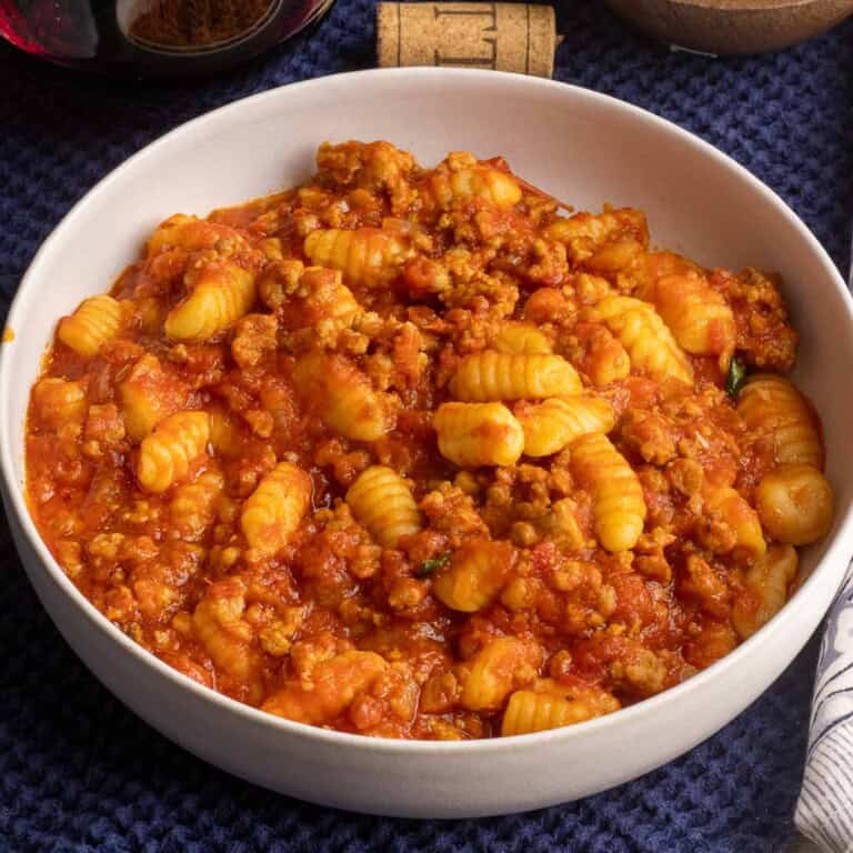 A white bowl of gnocchetti pasta in a ragu.