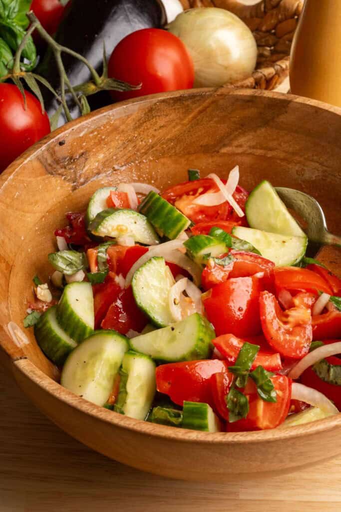 A wood bowl of Mediterranean cucumber and tomato salad.