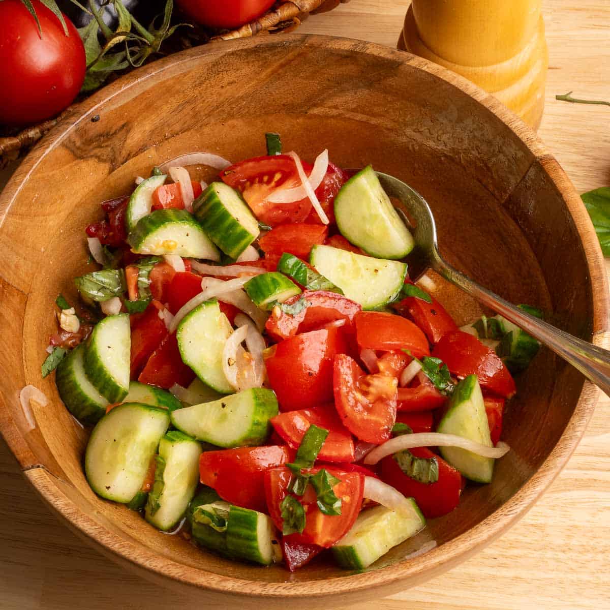 A wooden bowl filled with Mediterranean Tomato and Cucumber salad.
