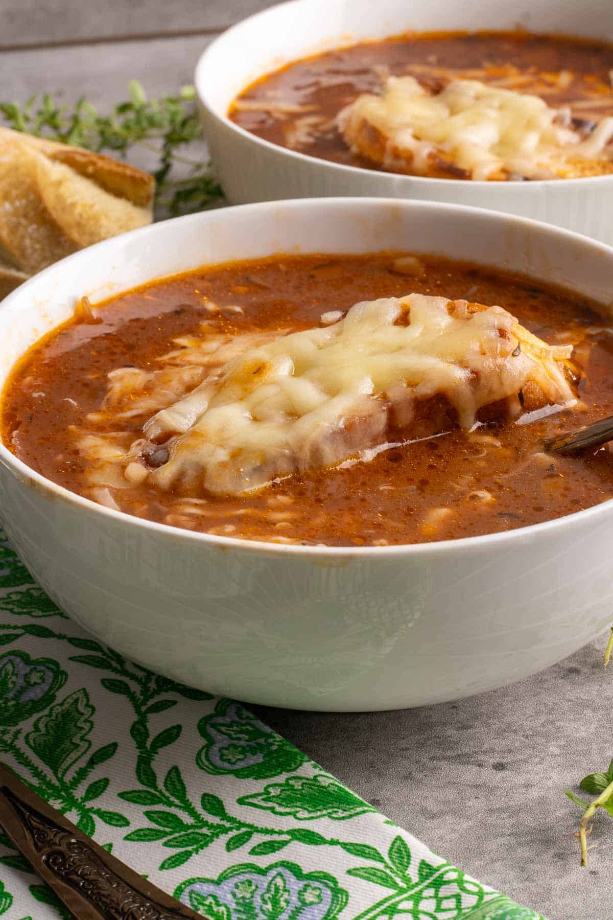 Two bowls of Carabaccia, Italian Onion Soup topped with a slice of bread and melted cheese.