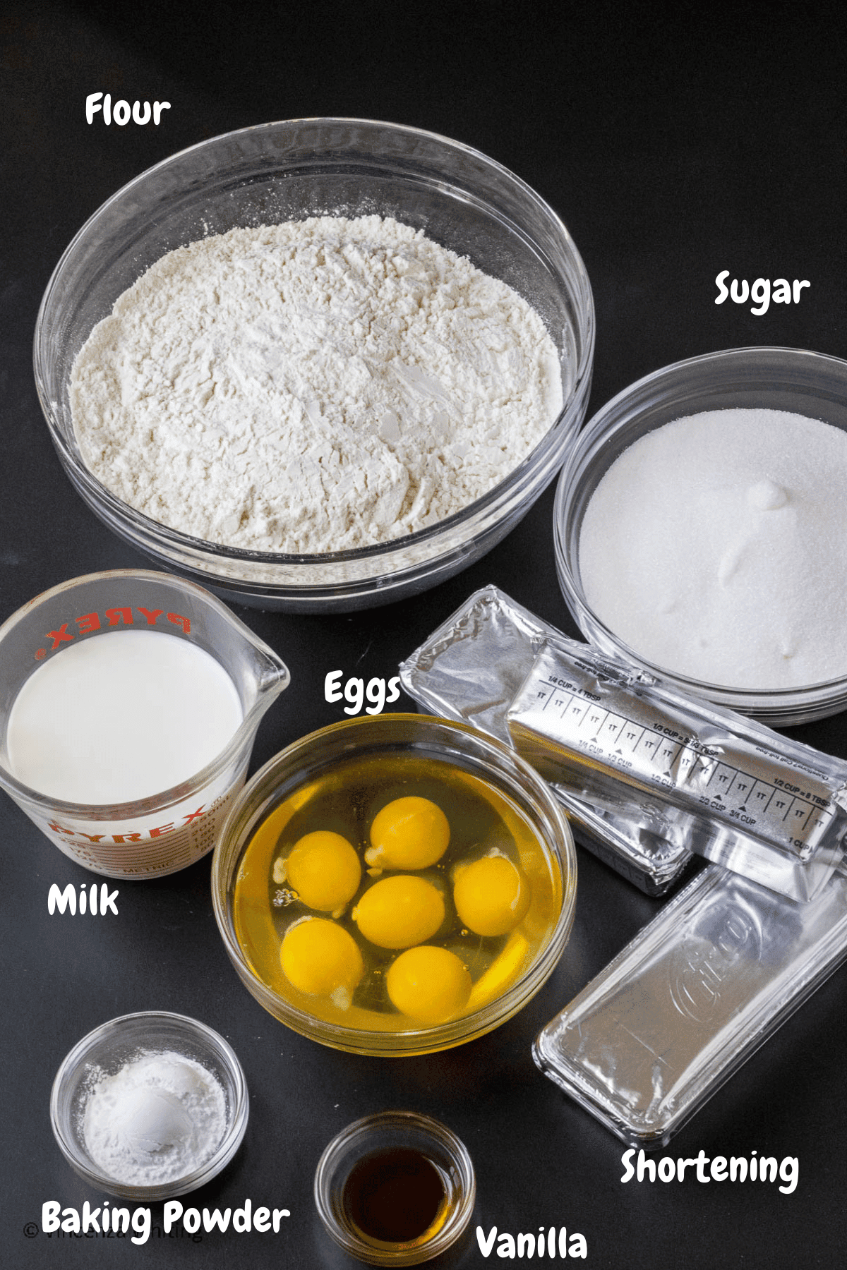 Ingredients for cookie dough on a black background with labels over each item.