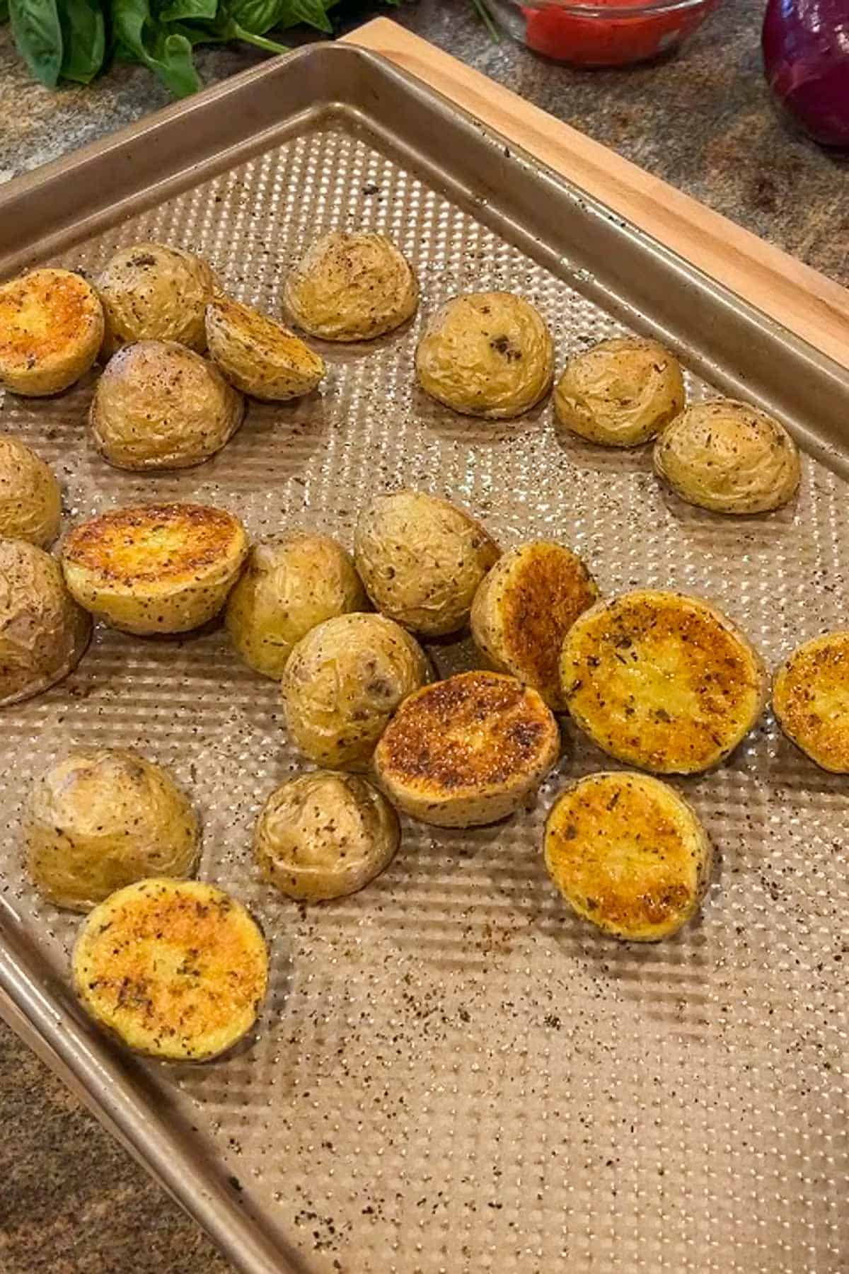 Roasted baby potato halves on a baking sheet.