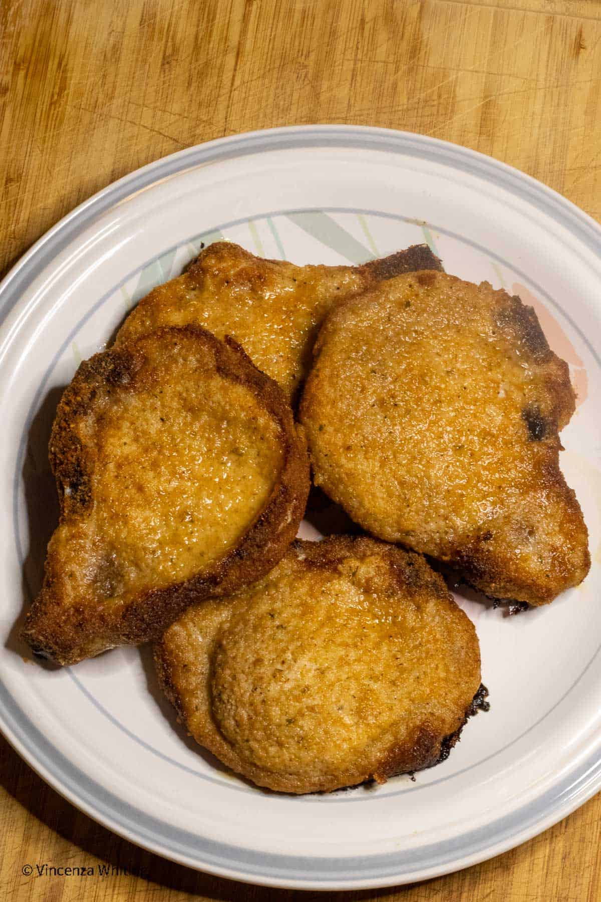 Breaded pork chops on a round plate.