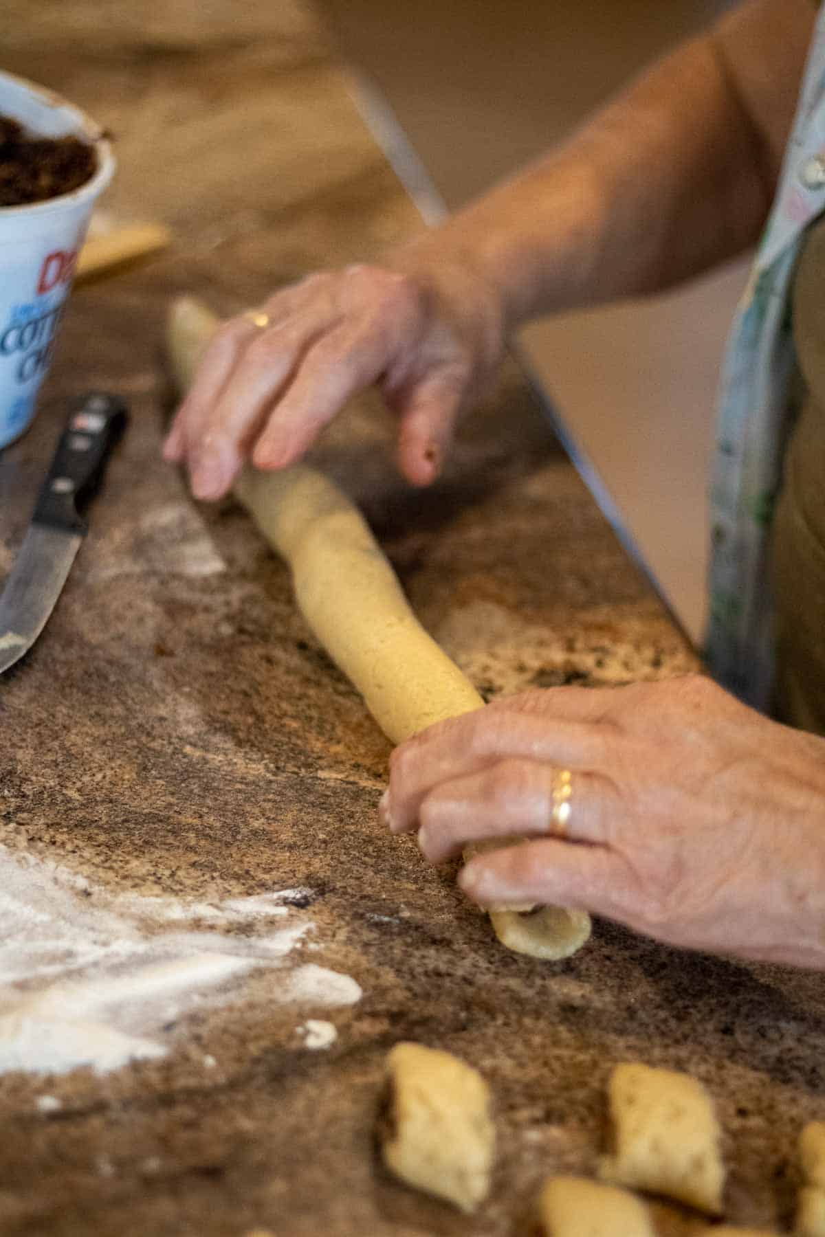 Cuccidati being rolled and cut into individual cookies.