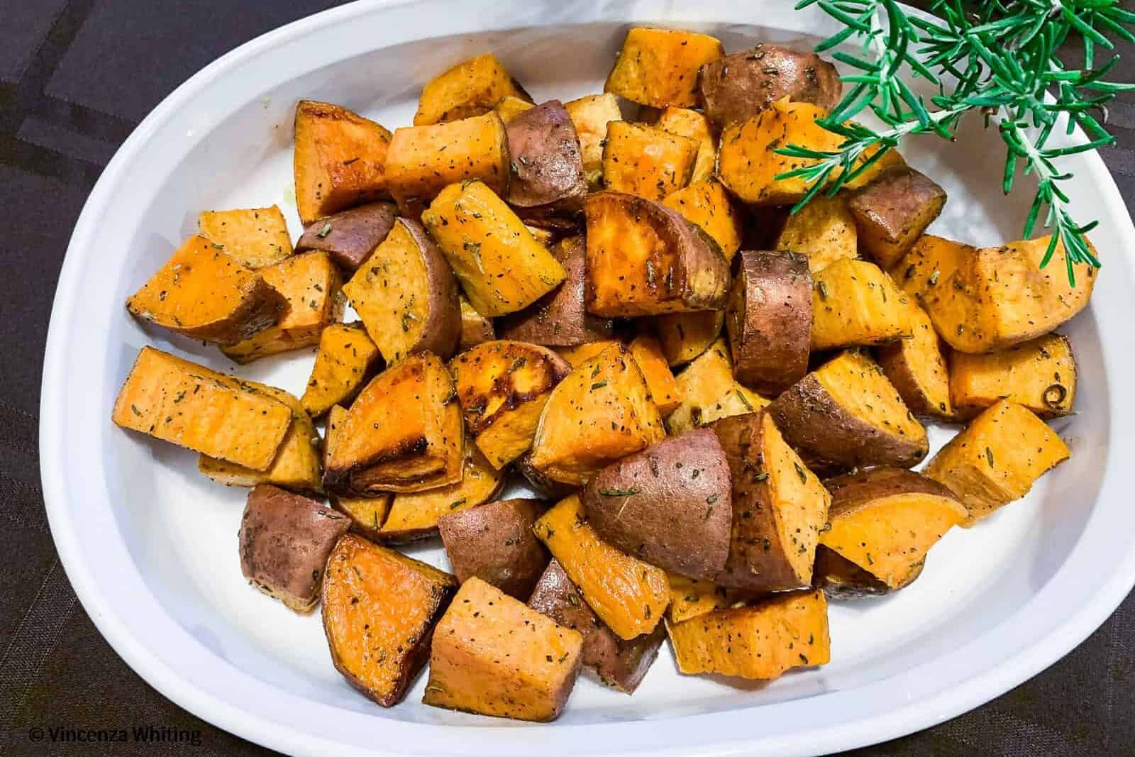 Rosemary Sweet potatoes are in a serving bowl with a sprig of rosemary and are ready to be served.