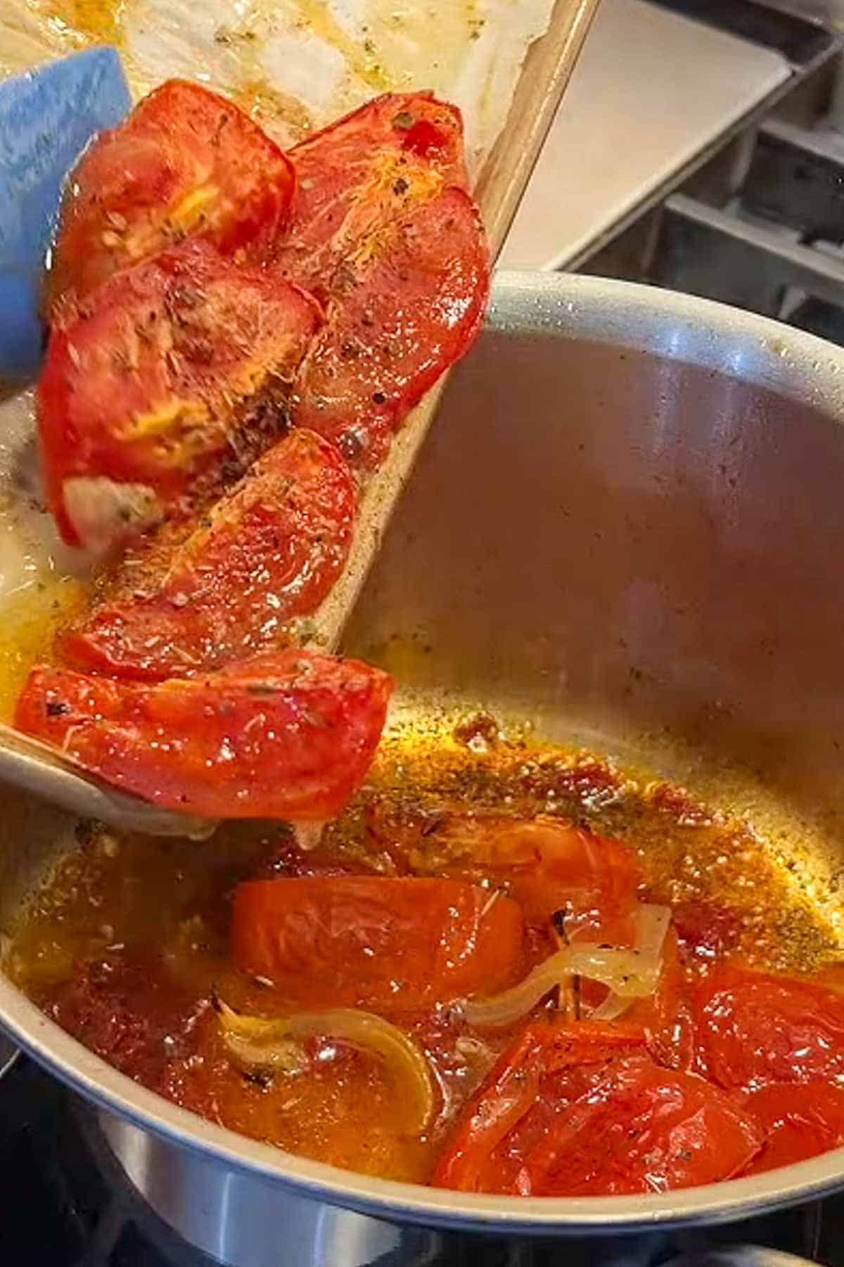 Roasted tomatoes being added to a sauce pan.