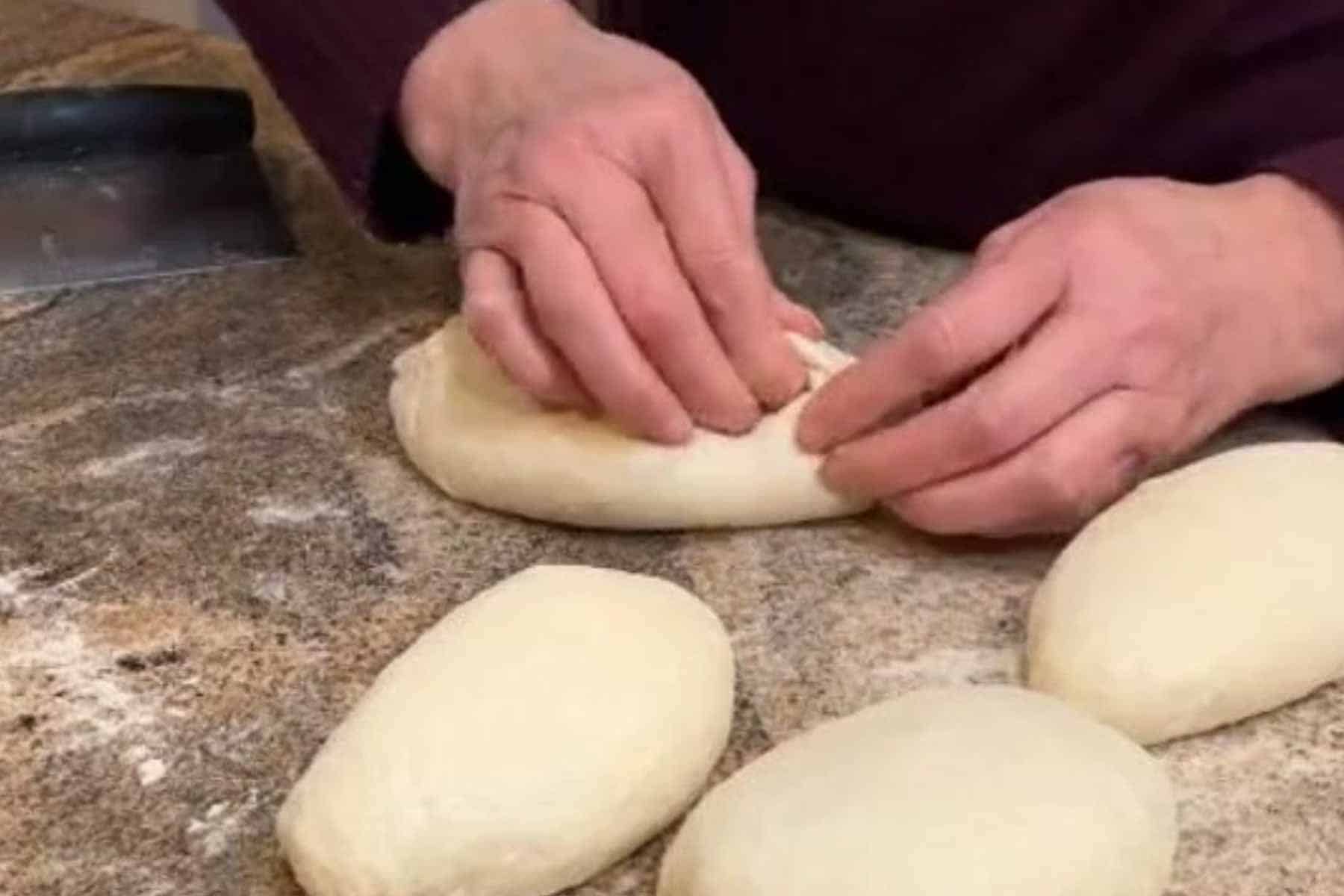 Pinching dough to form bread loaf.