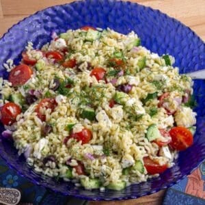 a blue bowl filled with a mediterranean orzo pasta salad.
