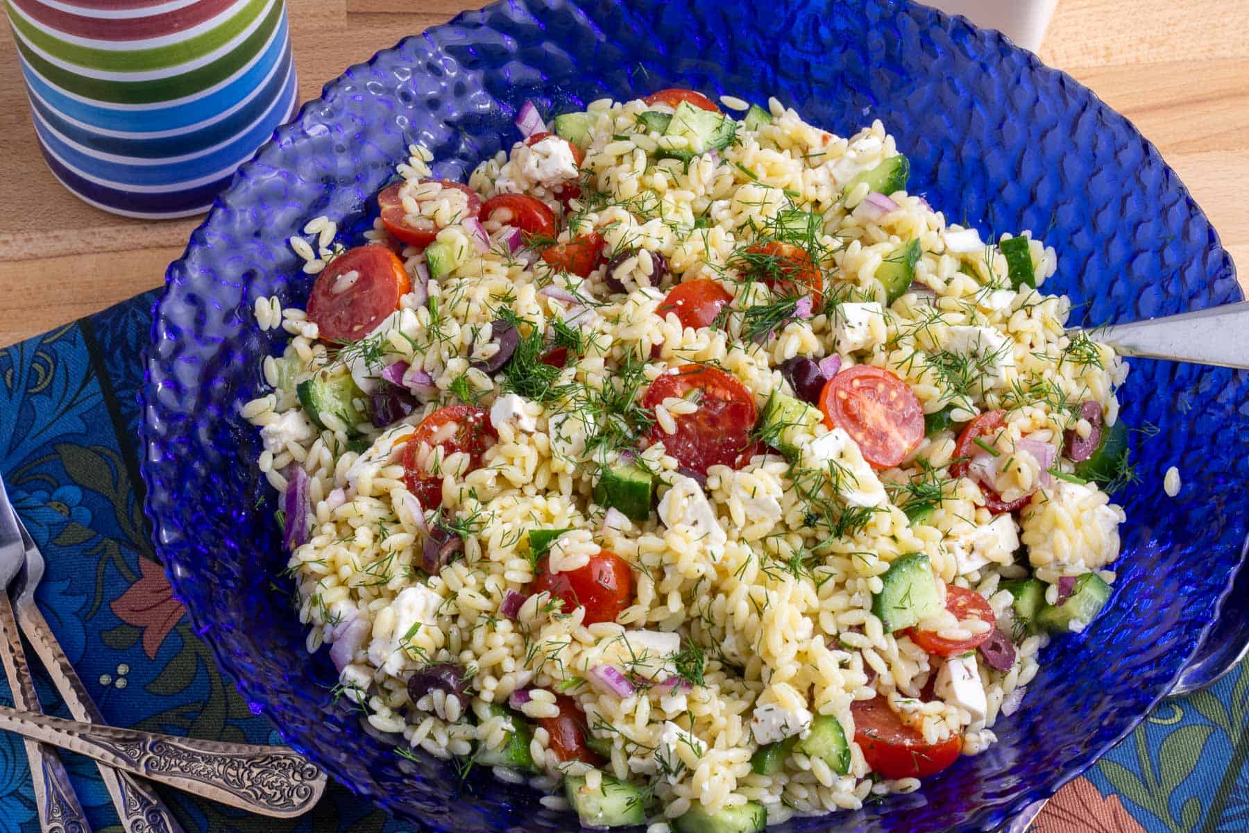 A blue bowl filled with  orzo pasta salad with feta and dill. 